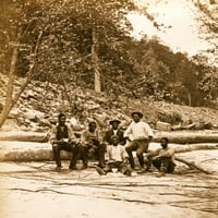 Posada broda afričkih američkih muškaraca koja sjedi na, a ispred, pala stabla u blizini nove rijeke,